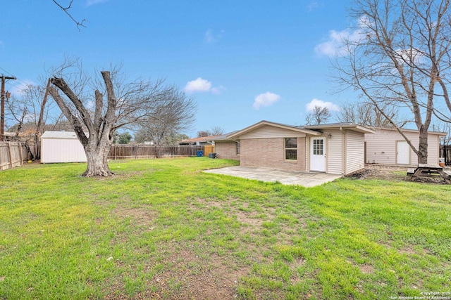 view of yard with an outbuilding, a patio area, a fenced backyard, and a shed