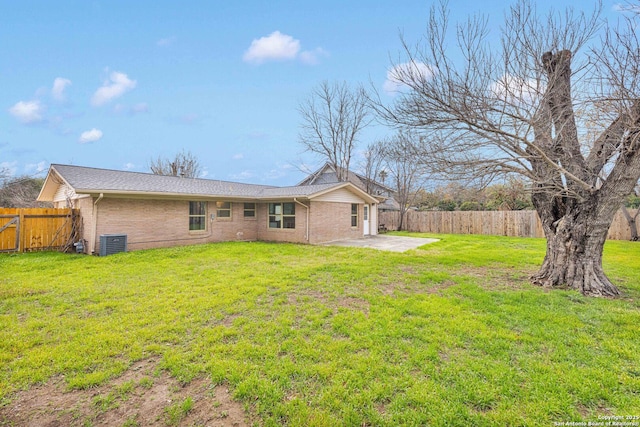 rear view of property with a yard, a fenced backyard, a patio, and central AC