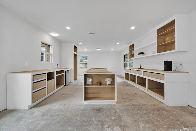 interior space with dishwasher, open shelves, concrete floors, and visible vents