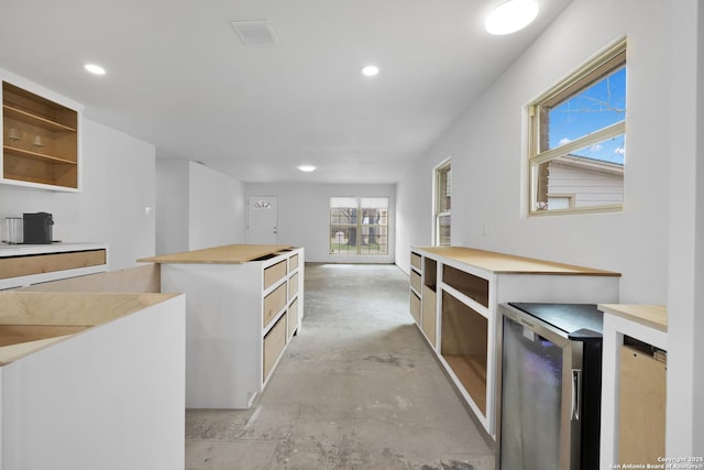 kitchen with visible vents, unfinished concrete floors, a center island, light countertops, and open shelves