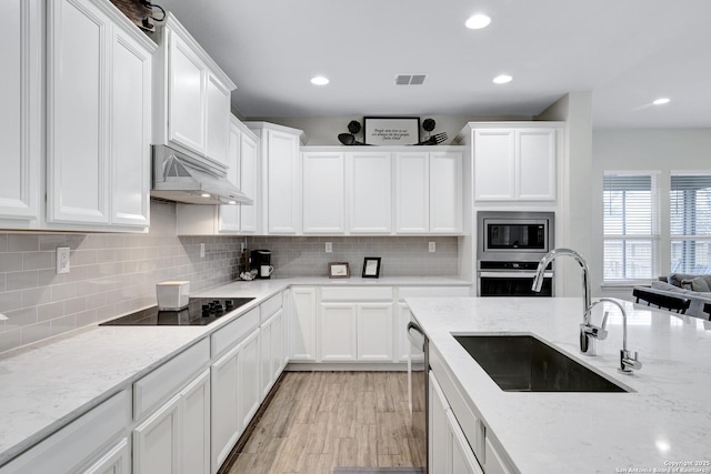 kitchen featuring light stone countertops, white cabinetry, stainless steel appliances, and a sink