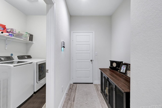 laundry area featuring laundry area, separate washer and dryer, light wood-style flooring, and baseboards