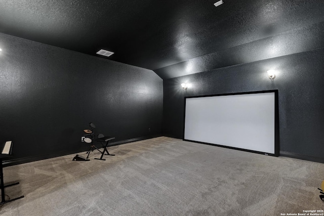 home theater with light colored carpet, visible vents, vaulted ceiling, a textured ceiling, and baseboards