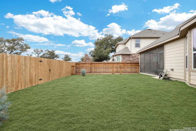 view of yard featuring a sunroom and a fenced backyard