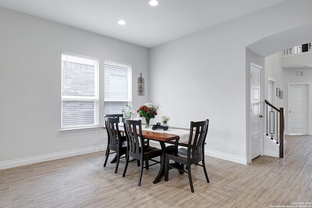 dining area featuring light wood-type flooring, baseboards, arched walkways, and recessed lighting