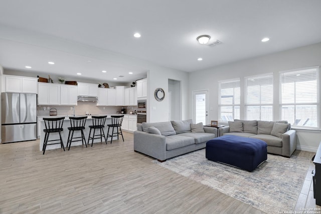 living area featuring baseboards, recessed lighting, visible vents, and light wood-style floors