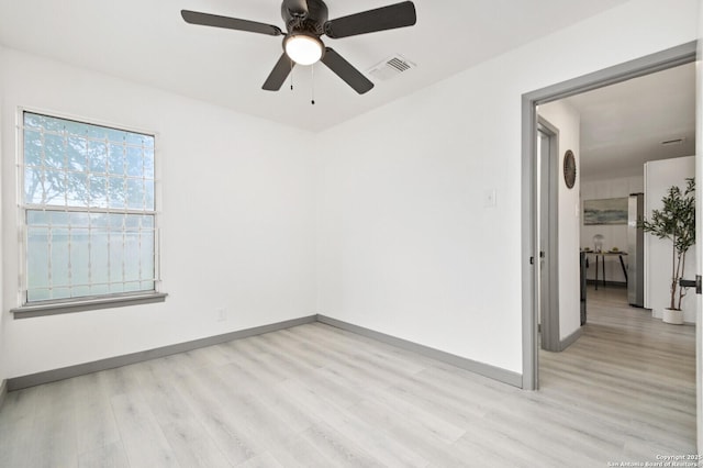 empty room with a ceiling fan, visible vents, light wood-style flooring, and baseboards