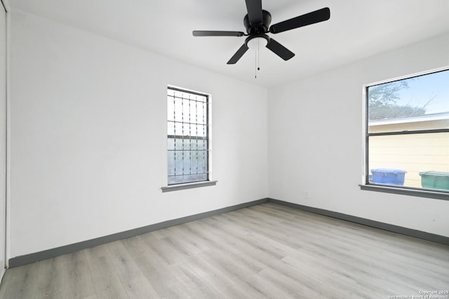 spare room featuring light wood-style flooring, baseboards, and a ceiling fan