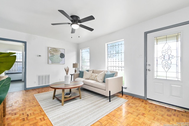 living area featuring a ceiling fan, visible vents, and baseboards