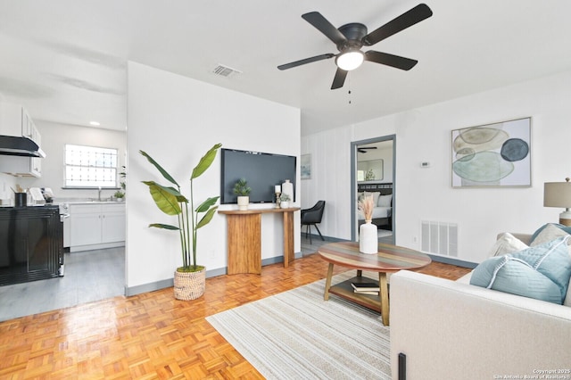 living room featuring baseboards, visible vents, and a ceiling fan