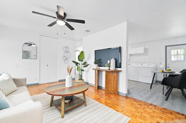 living area with parquet floors, washing machine and clothes dryer, visible vents, ceiling fan, and baseboards