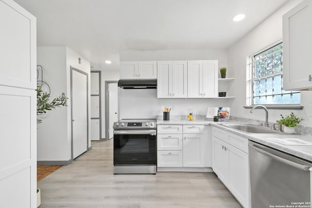 kitchen with white cabinets, appliances with stainless steel finishes, light countertops, under cabinet range hood, and a sink