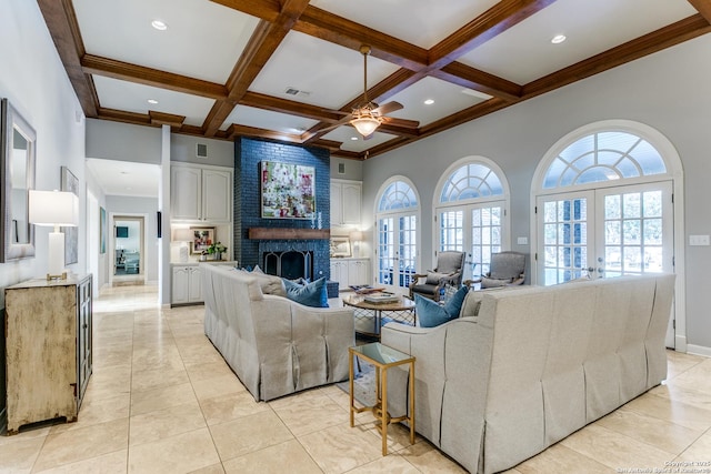 living area featuring a healthy amount of sunlight, a brick fireplace, coffered ceiling, and french doors