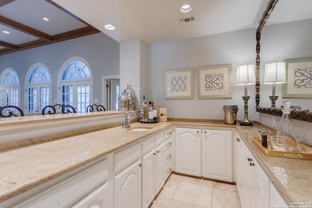 kitchen with visible vents, white cabinets, light stone countertops, a sink, and recessed lighting