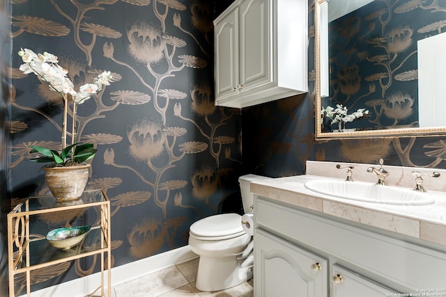 bathroom with toilet, vanity, baseboards, tile patterned floors, and wallpapered walls