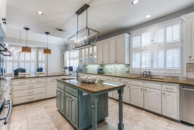 kitchen featuring visible vents, white cabinets, hanging light fixtures, stainless steel dishwasher, and a sink