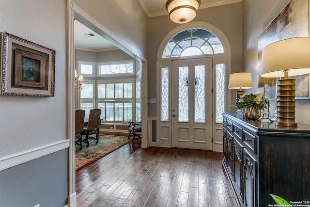 foyer with dark wood-style flooring, visible vents, and crown molding