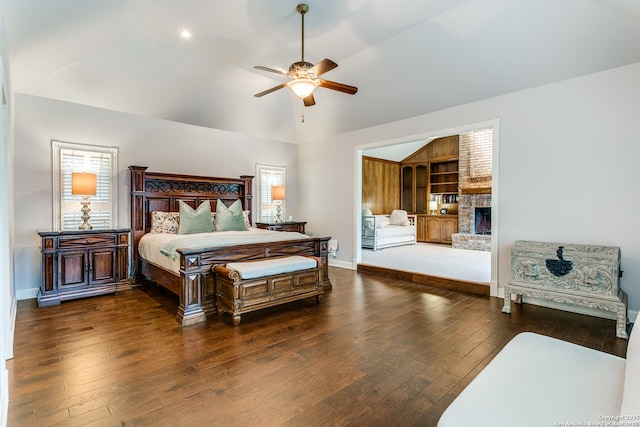 bedroom featuring lofted ceiling, dark wood-type flooring, a large fireplace, ceiling fan, and baseboards