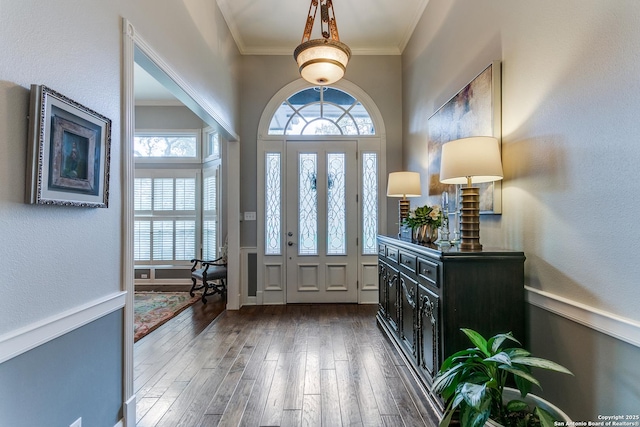 foyer entrance with dark wood-type flooring and crown molding