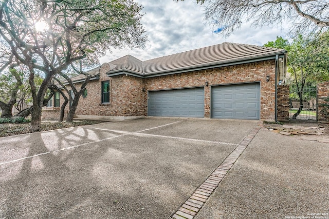 view of side of home featuring a garage, concrete driveway, brick siding, and a tiled roof