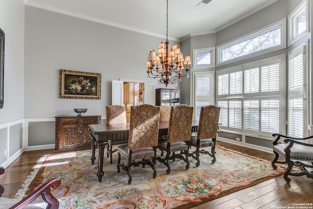 dining area with visible vents, ornamental molding, wood finished floors, a healthy amount of sunlight, and a chandelier