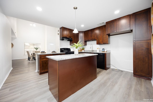 kitchen with a center island, under cabinet range hood, black appliances, pendant lighting, and a sink