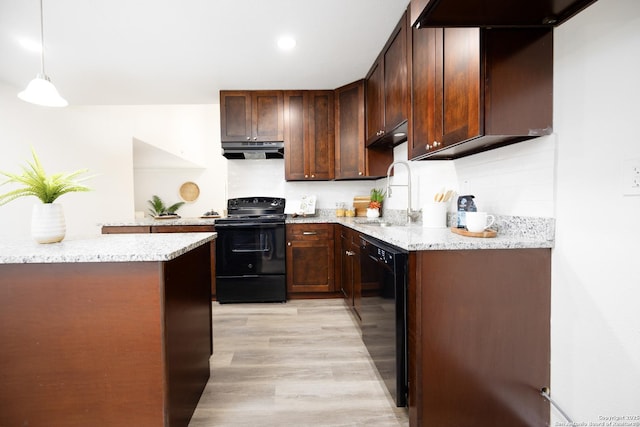 kitchen featuring light stone counters, under cabinet range hood, black appliances, pendant lighting, and a sink