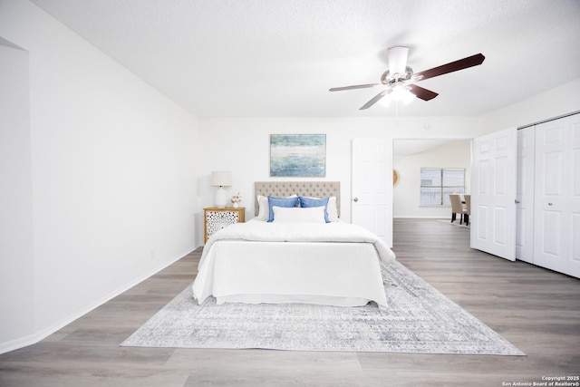 bedroom featuring a closet, dark wood-type flooring, ceiling fan, a textured ceiling, and baseboards