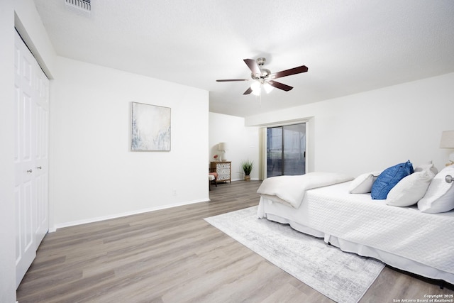 bedroom featuring a textured ceiling, wood finished floors, visible vents, and baseboards