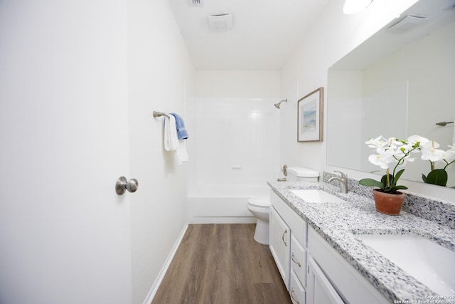 full bathroom featuring toilet, double vanity, a sink, and wood finished floors