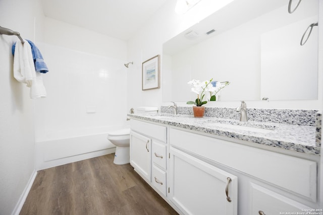 bathroom with double vanity, wood finished floors, a sink, and toilet