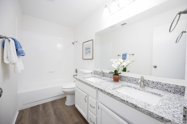 full bath with double vanity, wood finished floors, a sink, and toilet