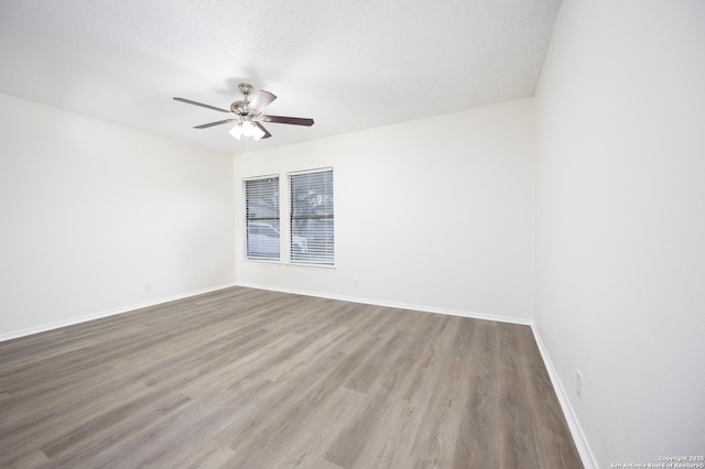 empty room featuring ceiling fan, a textured ceiling, light wood-style flooring, and baseboards