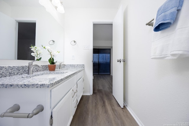 bathroom featuring wood finished floors, a sink, baseboards, and double vanity