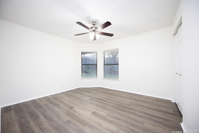 unfurnished room with ceiling fan, baseboards, and dark wood finished floors