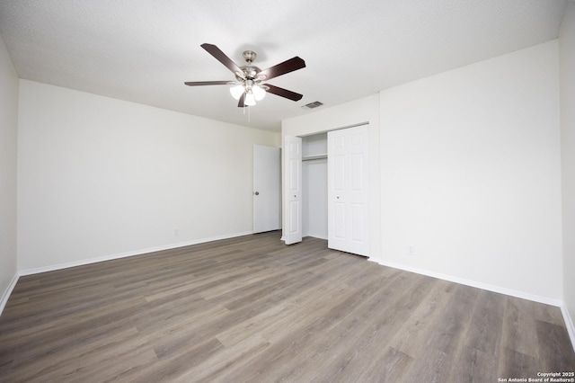 unfurnished bedroom with a closet, visible vents, baseboards, and wood finished floors