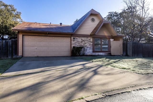 view of front facade with driveway, brick siding, an attached garage, and fence