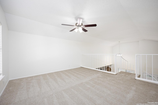 spare room with vaulted ceiling, ceiling fan with notable chandelier, carpet, and a textured ceiling