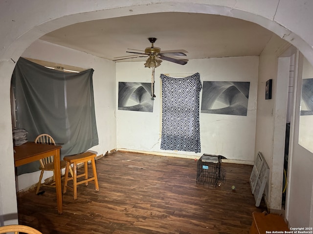 interior space with dark wood-style floors, arched walkways, and a ceiling fan