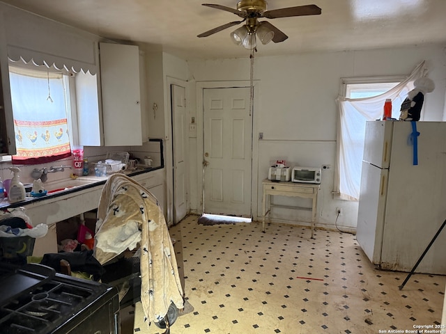 kitchen with freestanding refrigerator, a sink, ceiling fan, and light floors