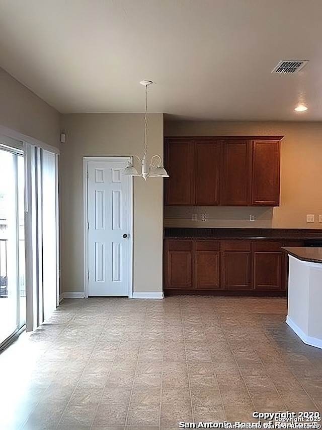 kitchen with baseboards, dark countertops, visible vents, and pendant lighting