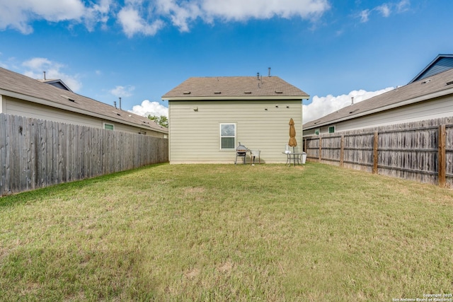 back of property with a fenced backyard and a yard