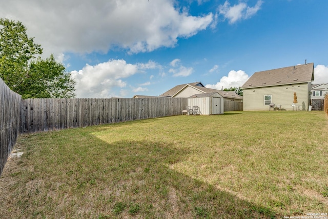 view of yard featuring a fenced backyard, a storage unit, and an outbuilding