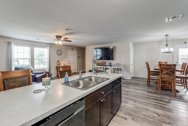 kitchen with light countertops, hanging light fixtures, light wood-style flooring, visible vents, and a sink