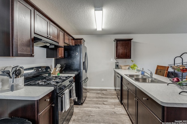 kitchen featuring under cabinet range hood, a sink, light countertops, black range with gas stovetop, and dishwasher