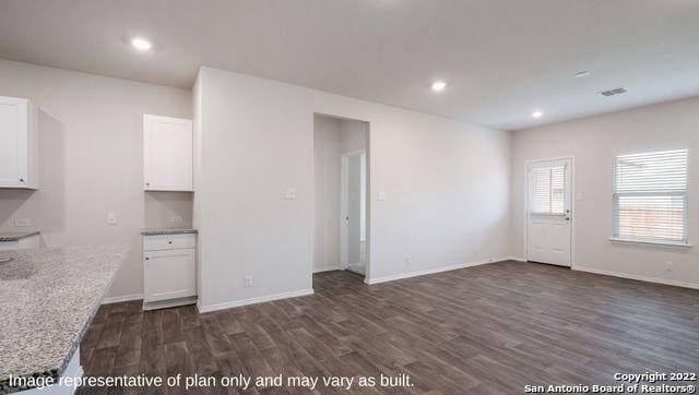 unfurnished living room featuring dark wood-type flooring, recessed lighting, and baseboards