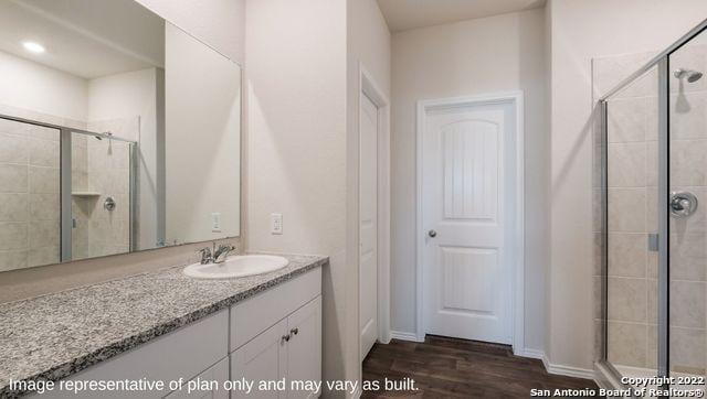 bathroom featuring a shower stall, wood finished floors, and vanity