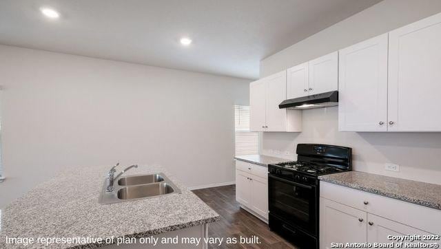 kitchen featuring white cabinetry, a sink, under cabinet range hood, and black range with gas stovetop