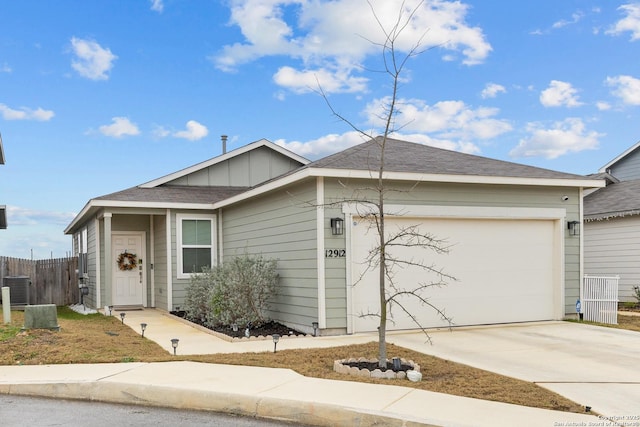 single story home with an attached garage, central air condition unit, fence, concrete driveway, and board and batten siding