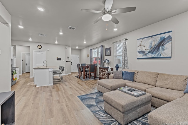 living room featuring a ceiling fan, recessed lighting, visible vents, and light wood finished floors